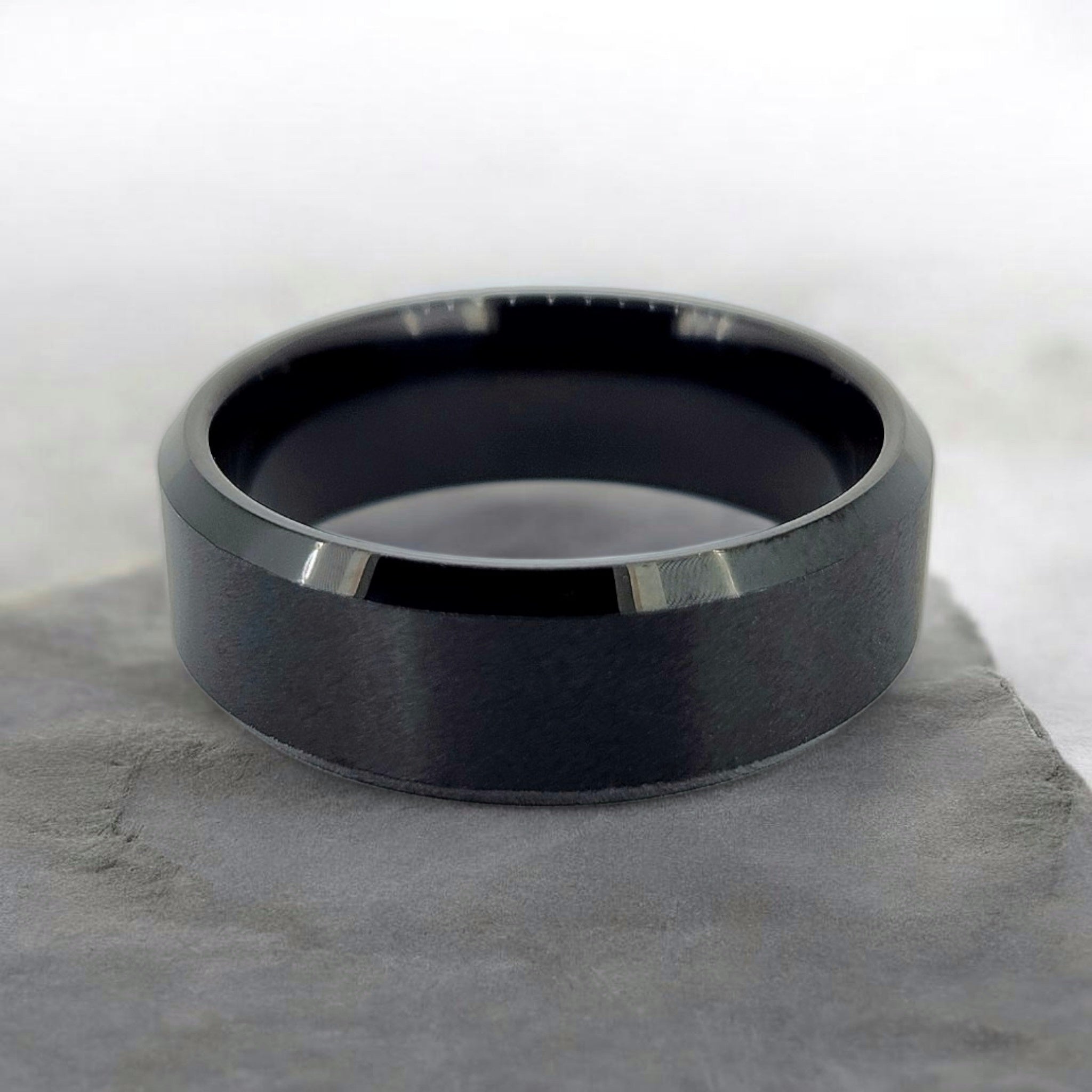 Black tungsten ring with matte finish and beveled edges shown flat on surface