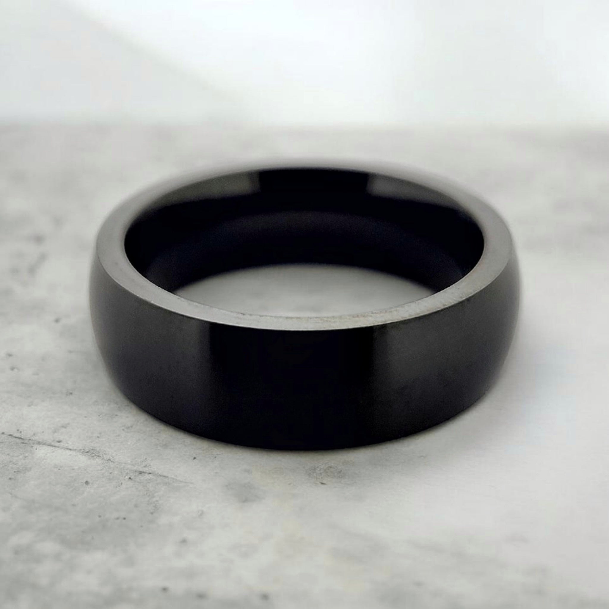 Black domed tungsten ring with matte finish shown flat on industrial surface