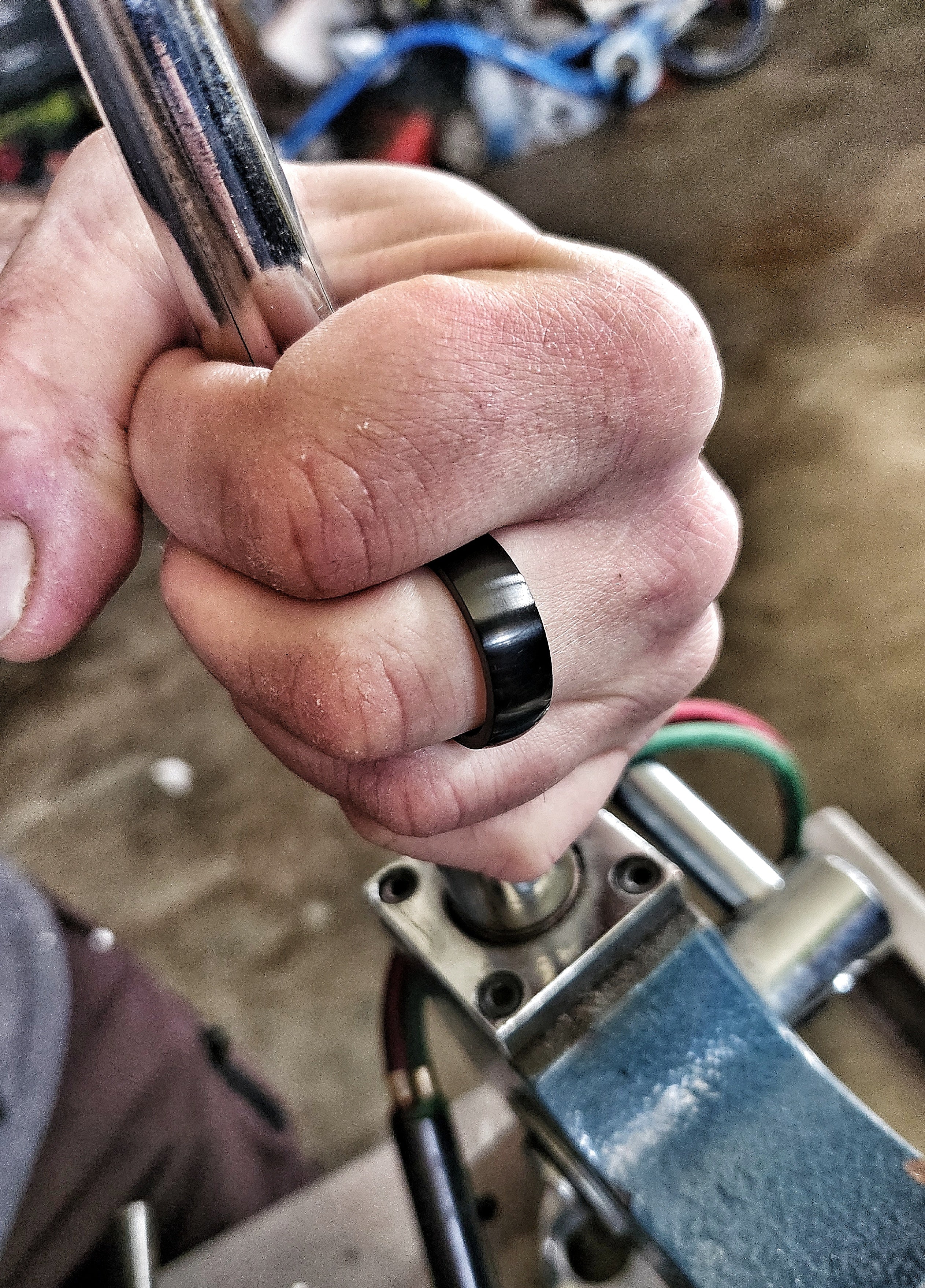 Men’s black domed tungsten ring worn on hand in rugged workshop setting