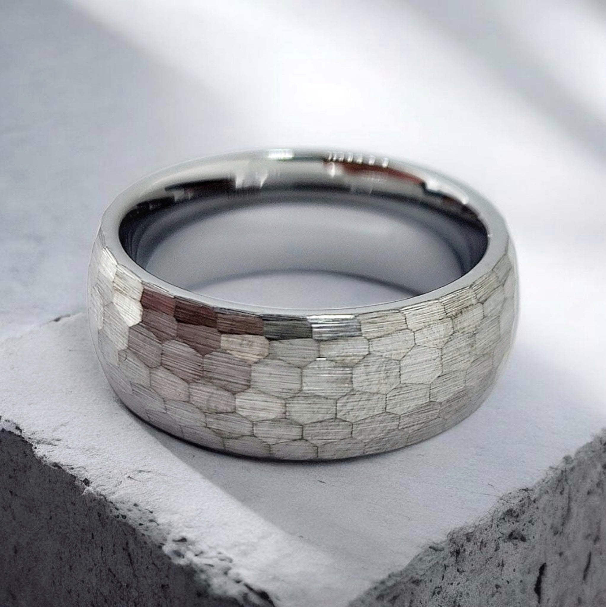Gunmetal hammered tungsten ring with matte texture shown flat on surface
