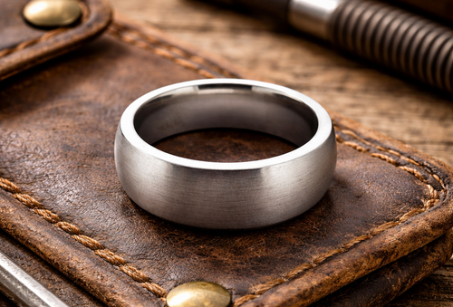 Men’s silver tungsten domed ring with matte finish in industrial workshop setting